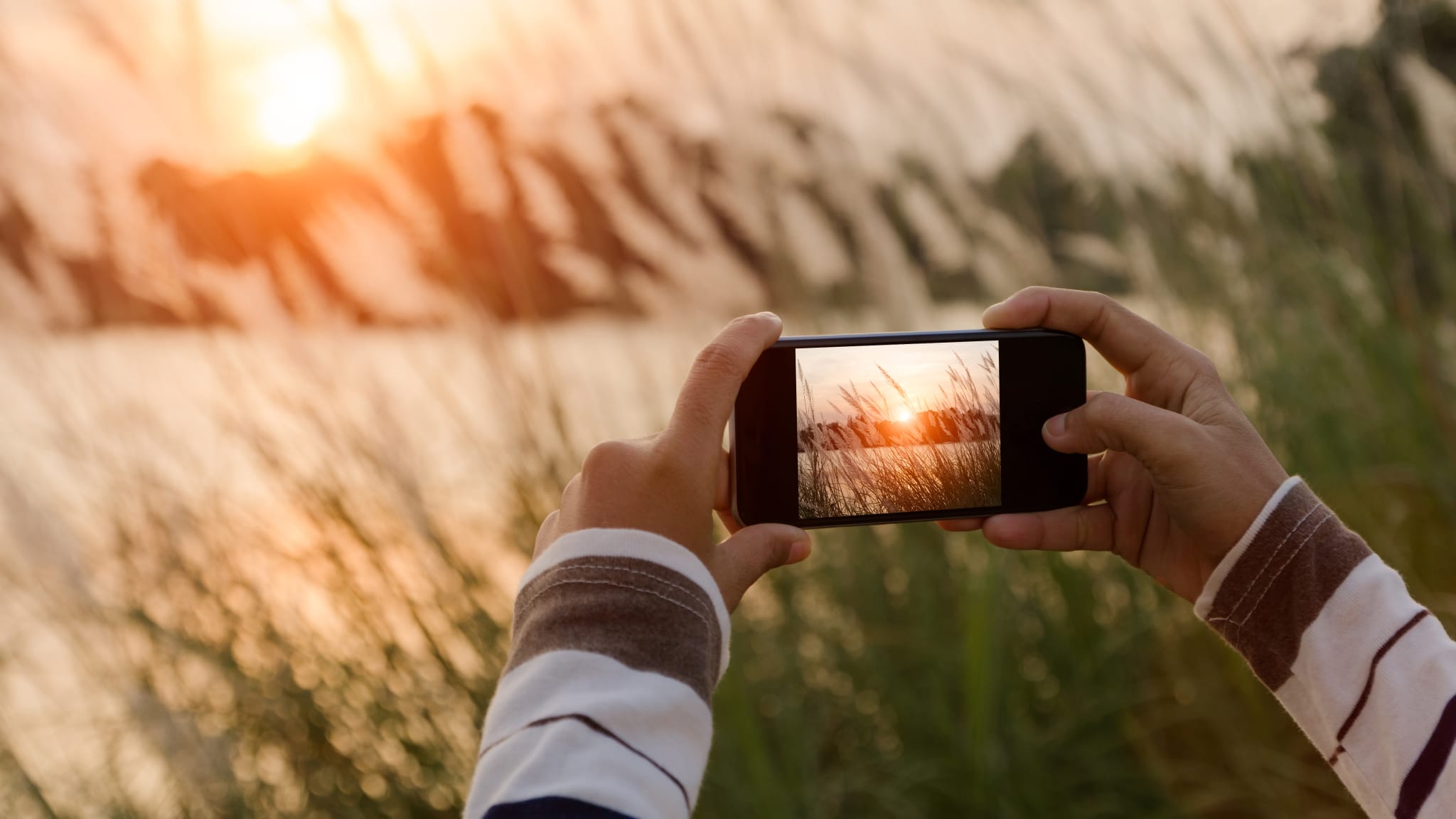 Mann macht ein Bild von einem See mit einem Smartphone