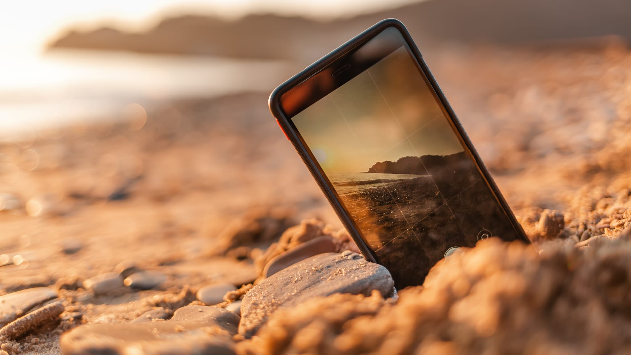 Ein Smartphone steck im Sand am Strand