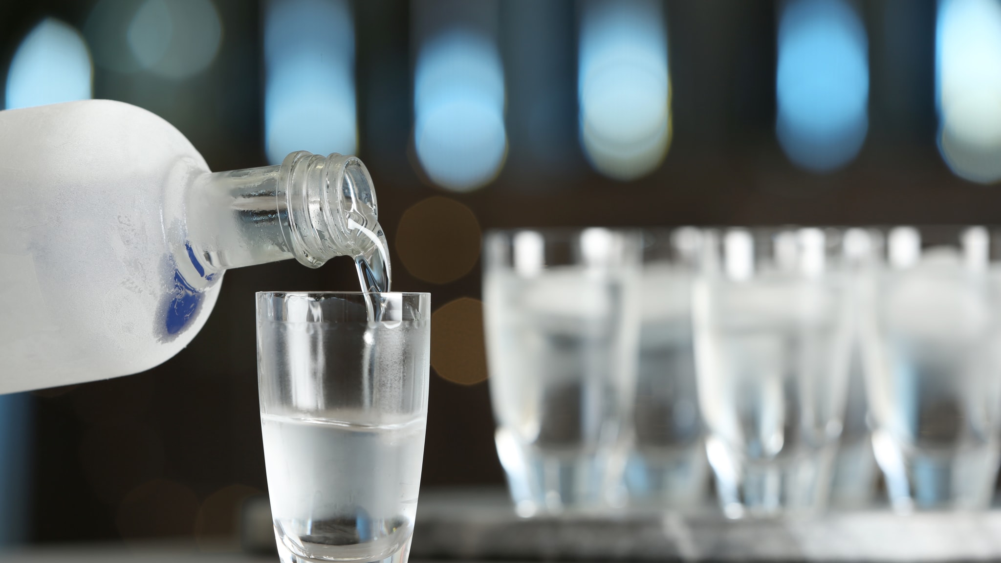 Wodka wird aus einer Flasche in ein Snapsglas gefüllt
