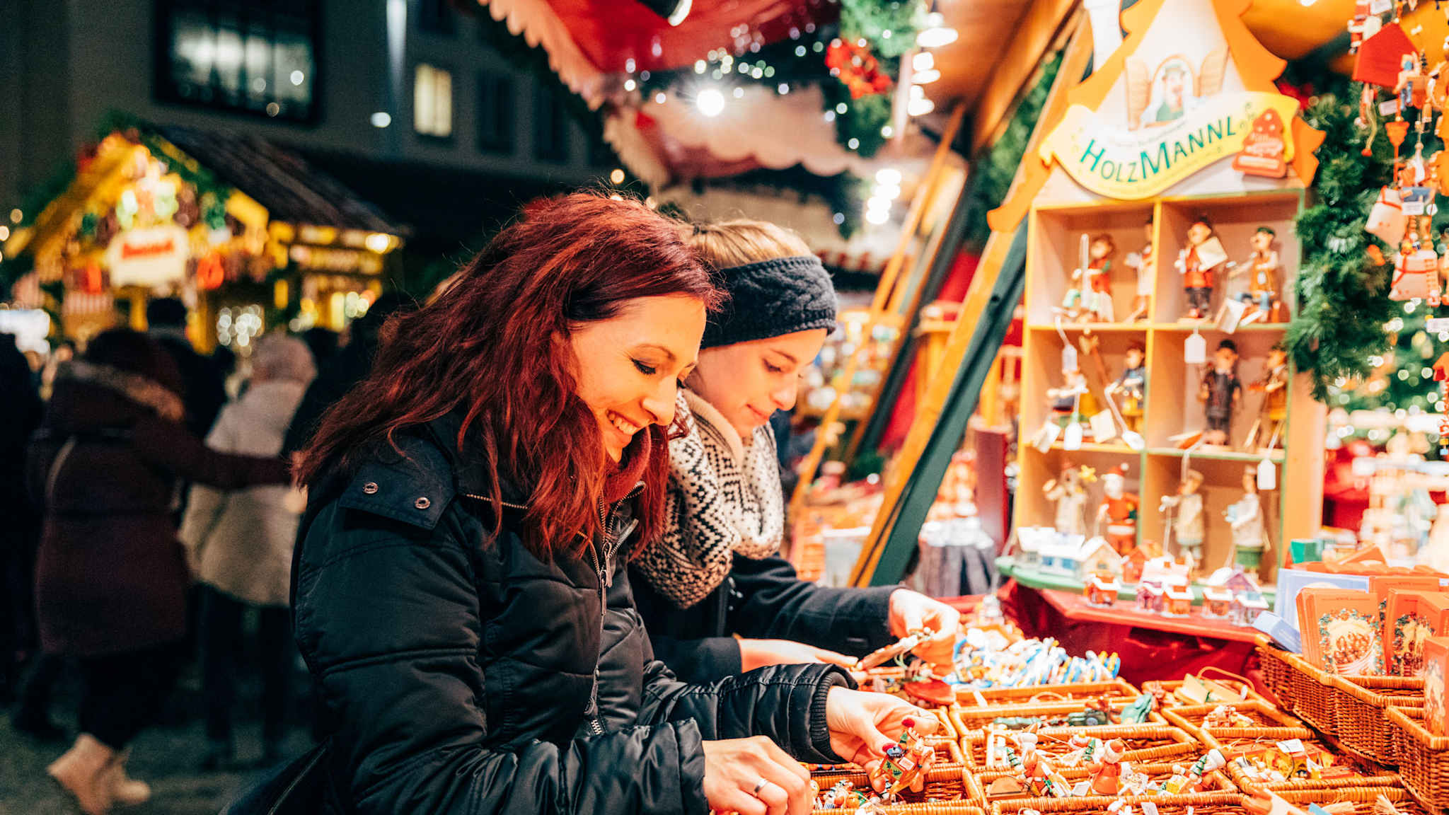 Zwei Frauen stöbern an einem Stand mit Holzpuppen