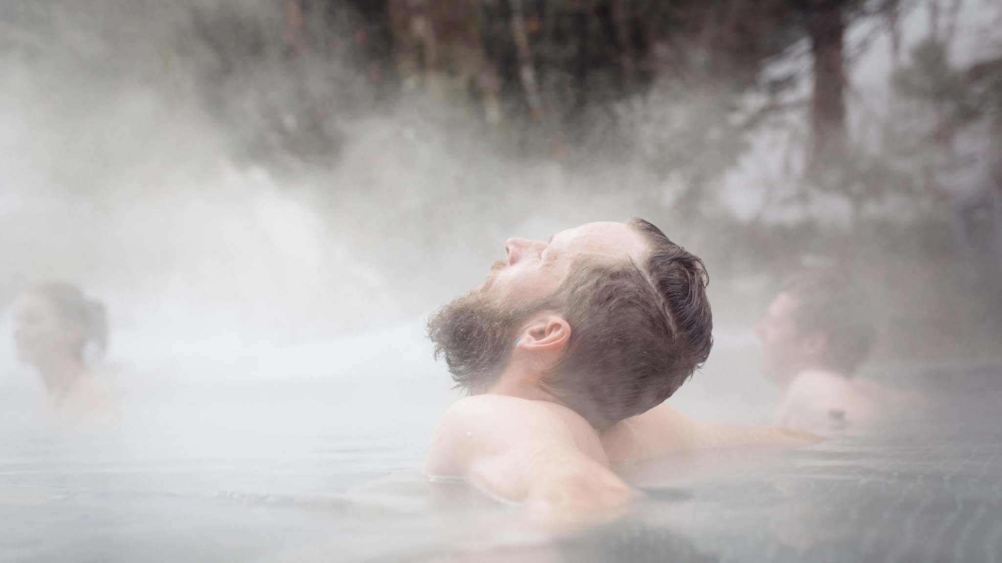 Ein Man sitzt in einem Pool. Es dampft.