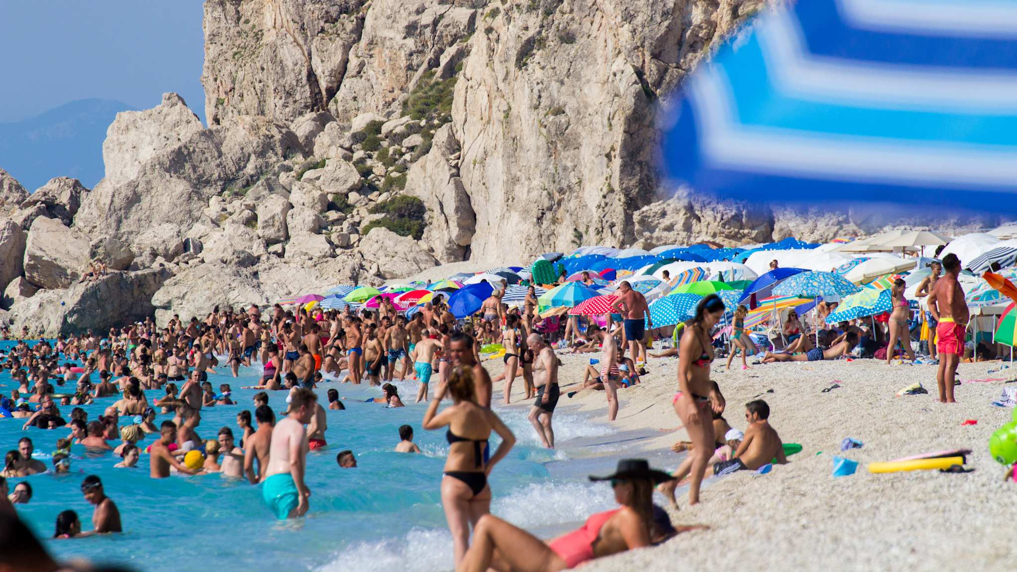 Strand neben felsiger Landschaft mit sehr vielen Menschen