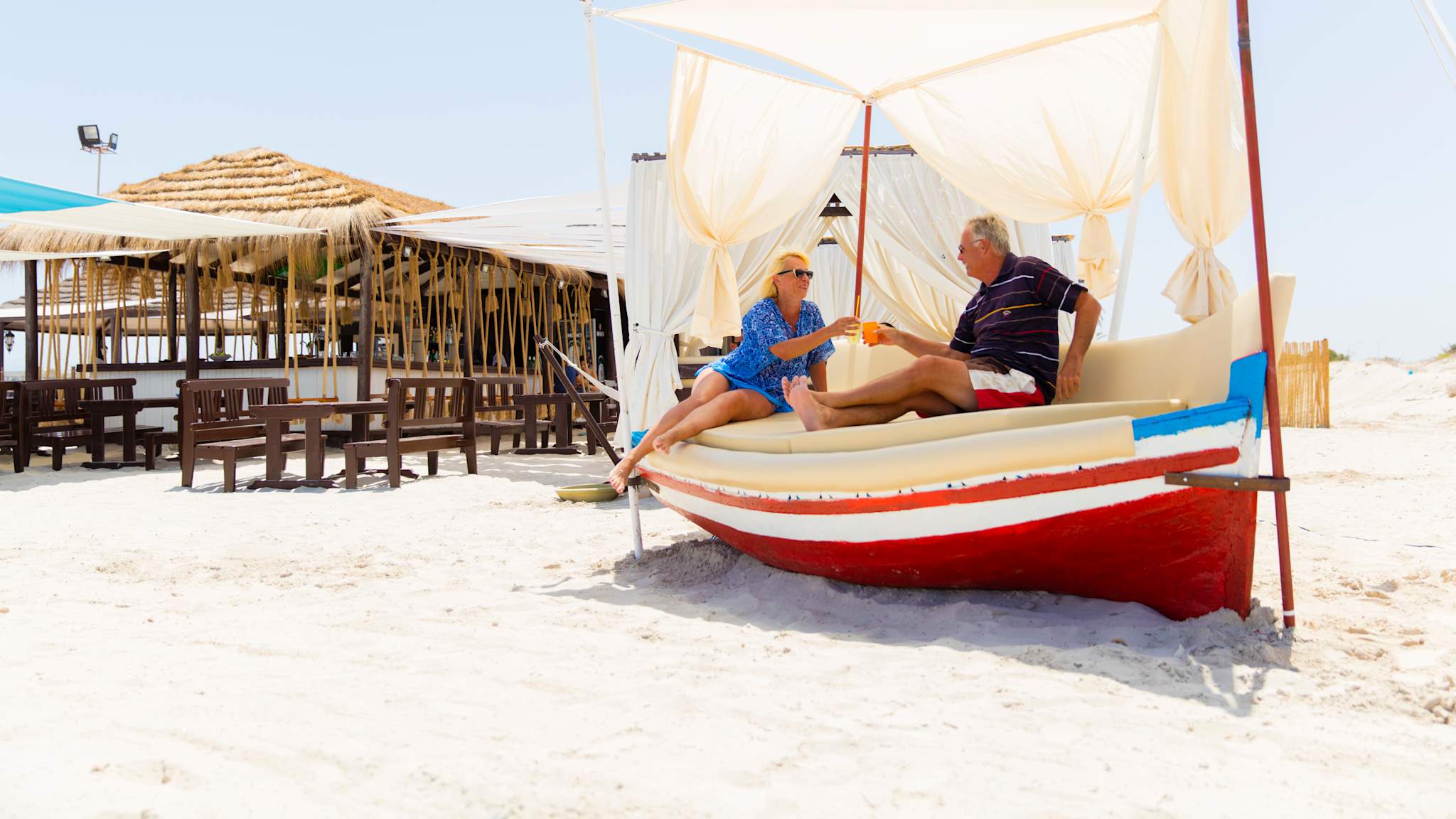 Pärchen stoßt am Strand mit Drinks an.