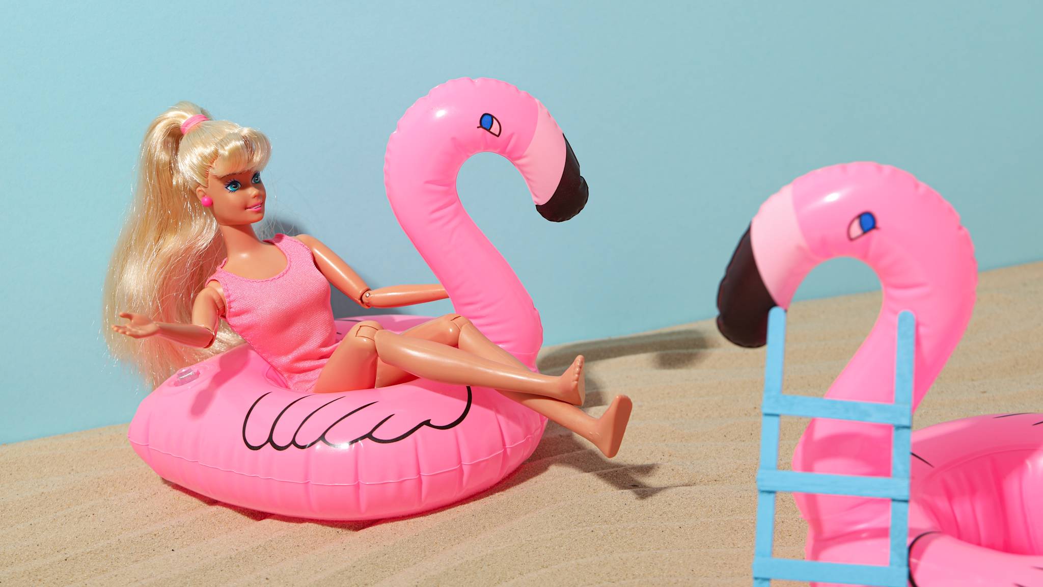 Barbie-Puppe im Badeanzug auf aufblasbarem Flamingo am Strand