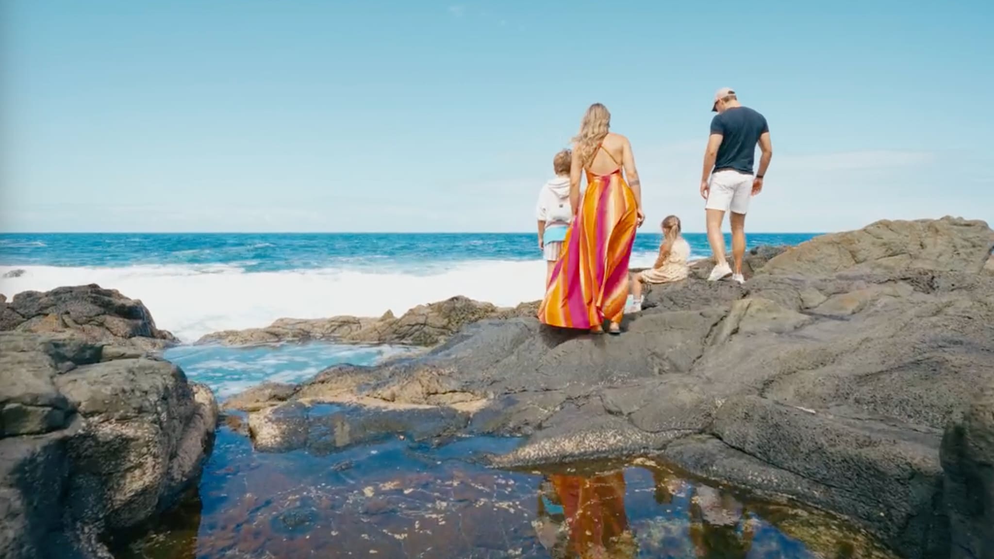 Mutter, Vater und zwei Kinder an einem steinigen Strand auf Fuerteventura, Kanaren.