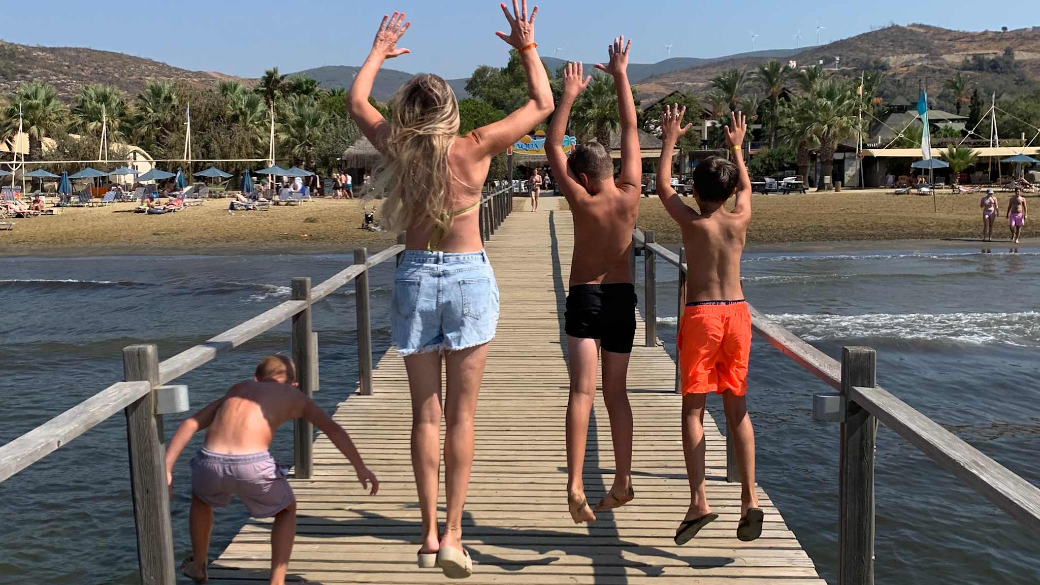 Frau mit drei Jungs auf einen Steg im Meer.