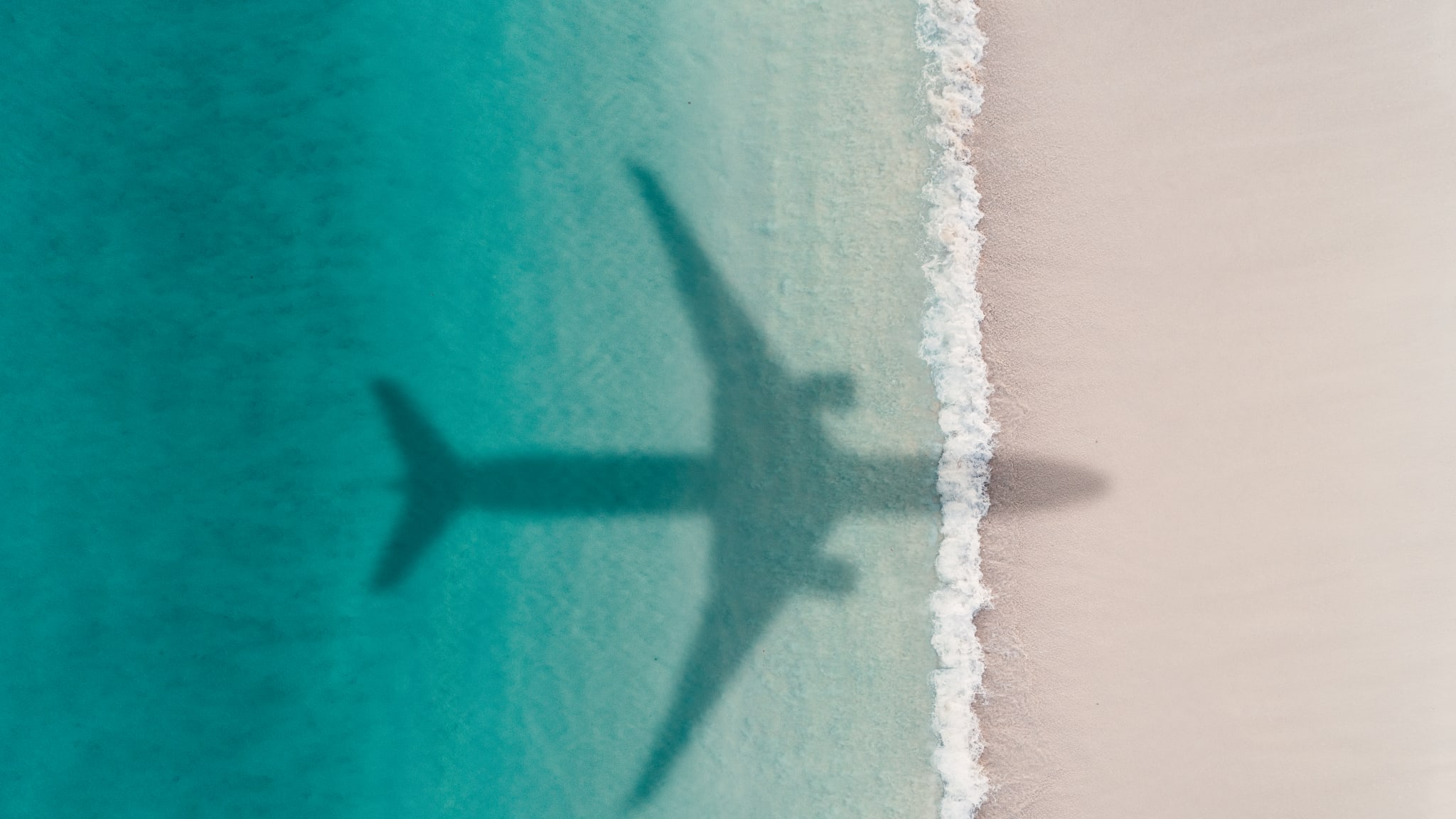 Flugzeug fliegt über Strand.