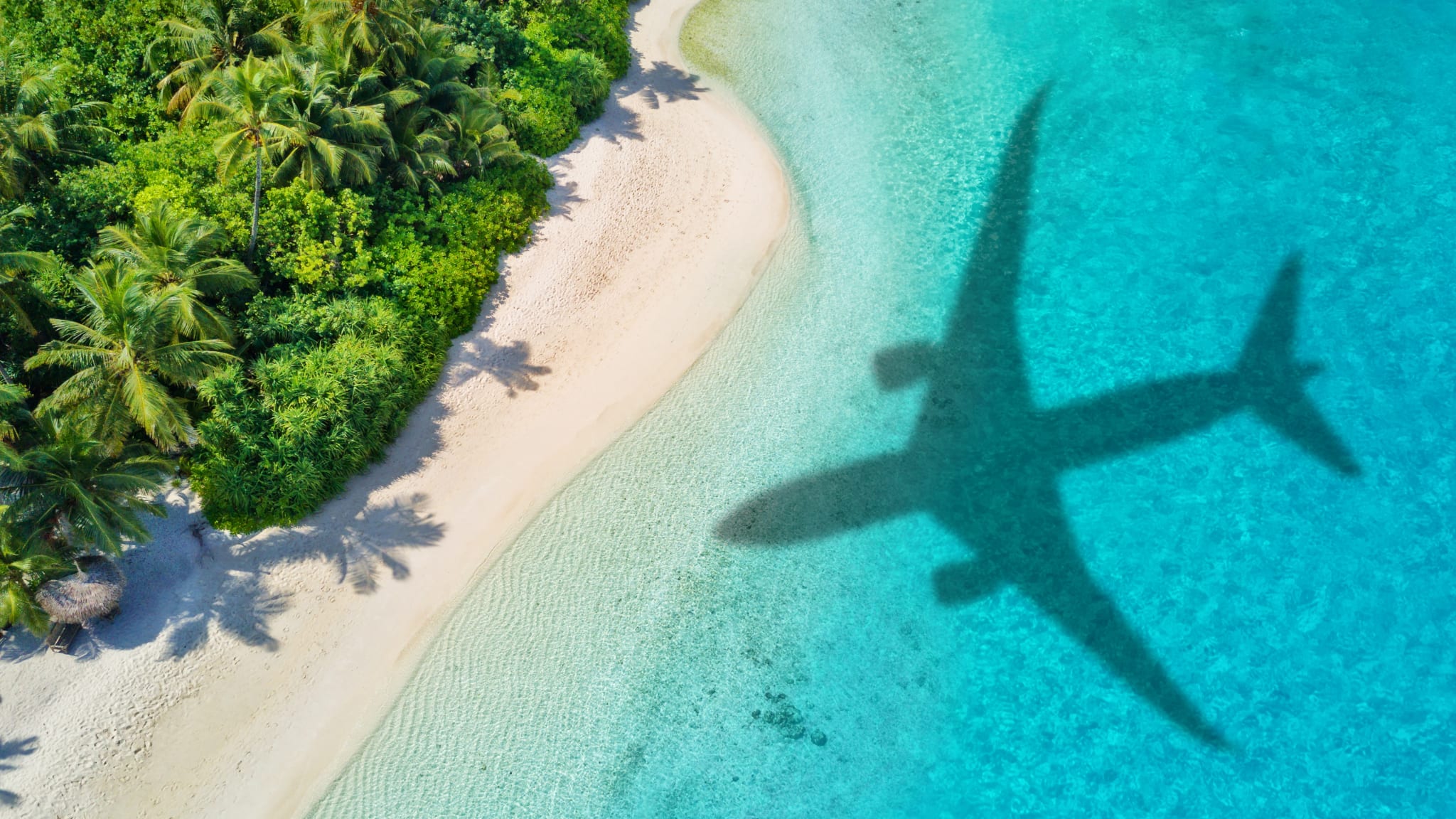 Flugzeugschatten im kristallkaltem Meer an einem tropischen Strand.