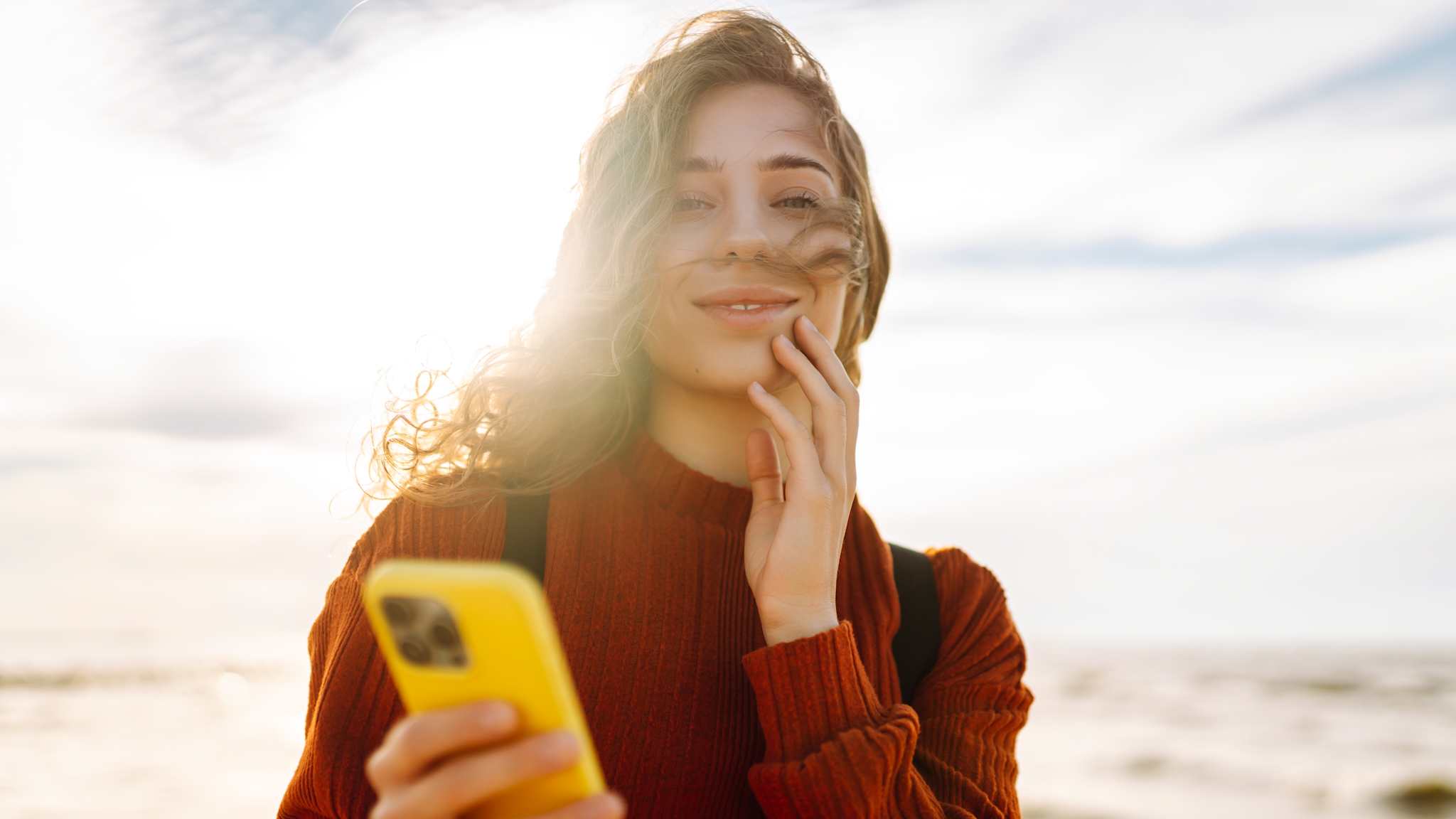 Frau mit Smartphone am Strand.