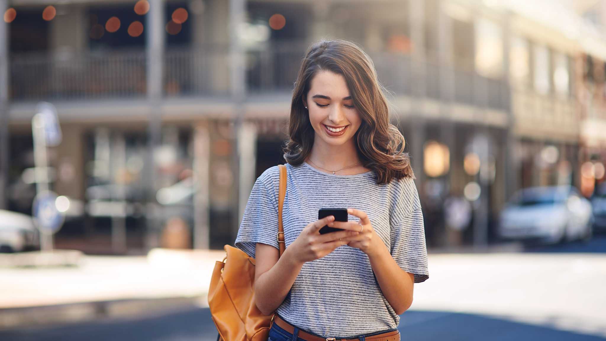 Frau schaut lächelnd auf ihr Smartphone