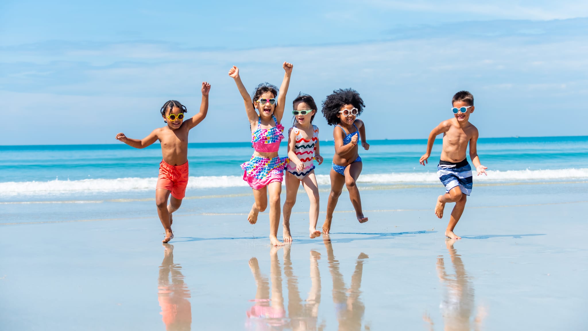 Eine fröhliche Kinderschar läuft am Strand entlang.