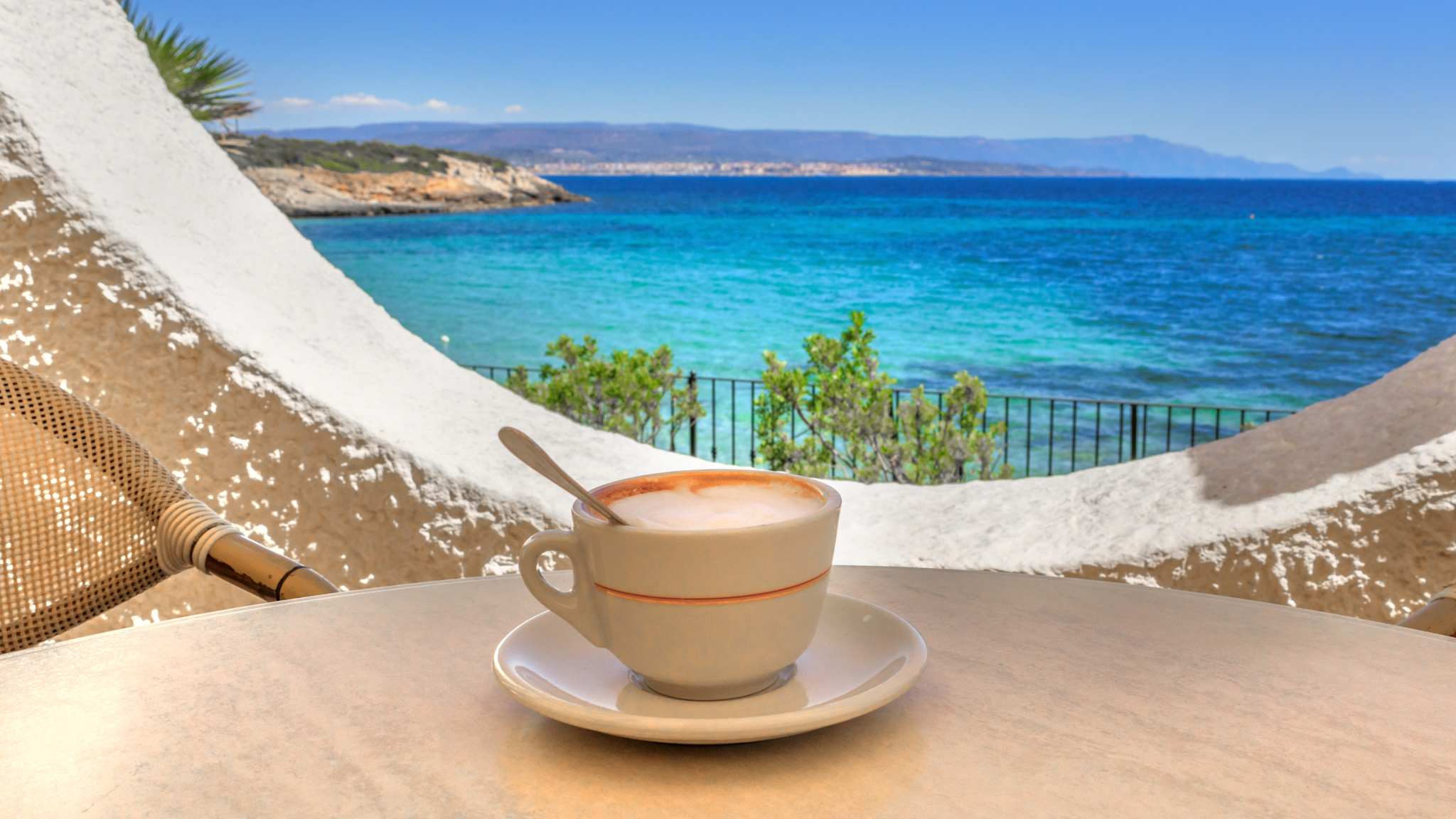 Eine Kaffeetasse auf einem Tisch mit Blick auf das Meer.