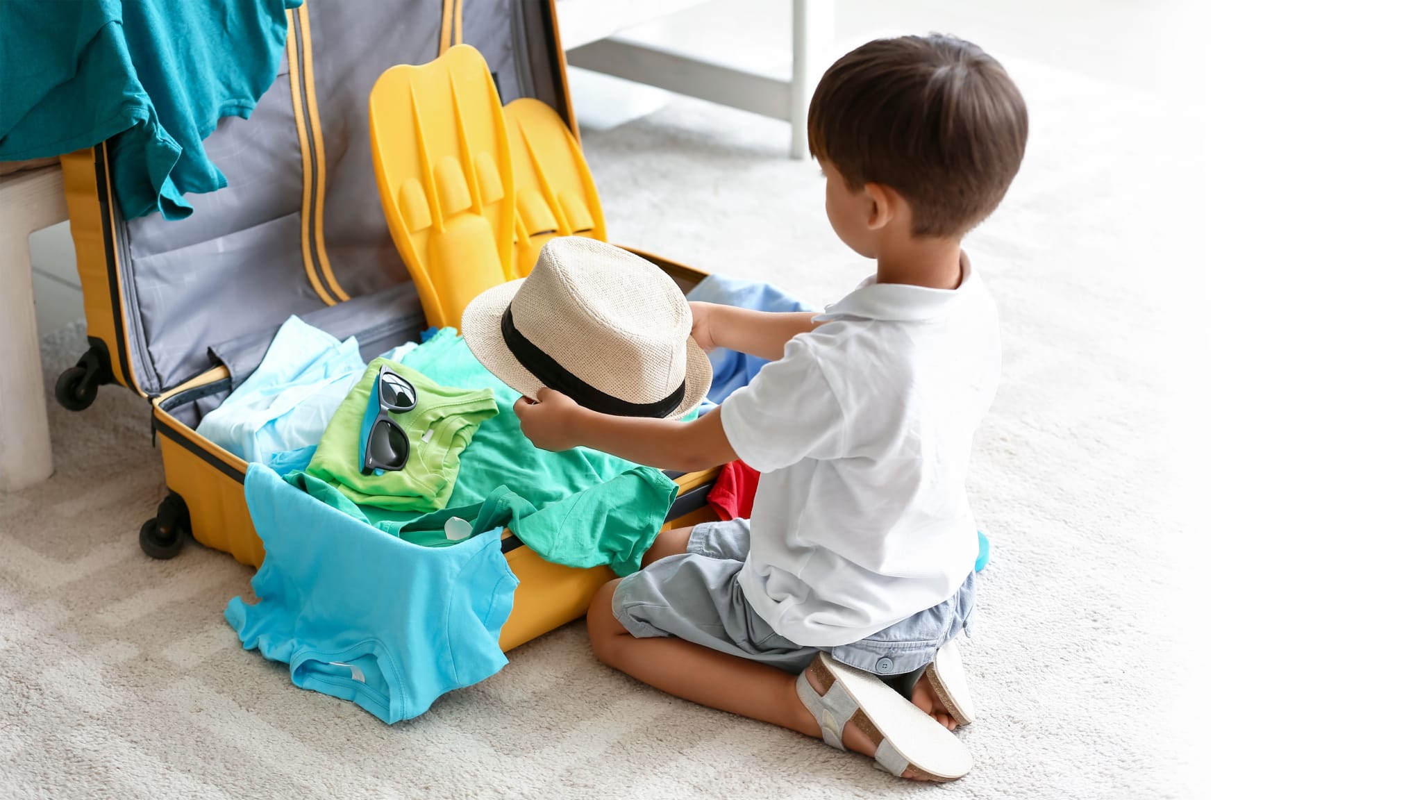 Junge packt Sachen in den Koffer.