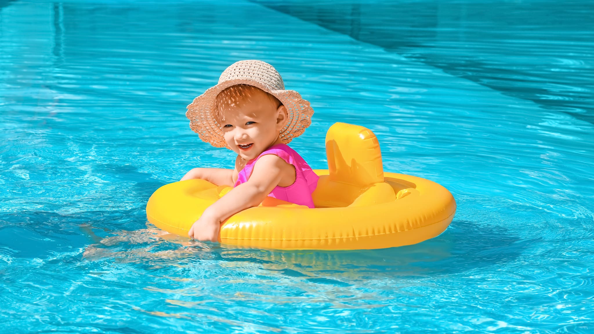 Kleines Mädchen in Pool in einem gelben Schwimmring.