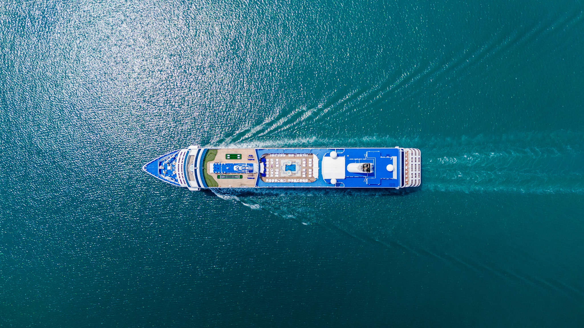 Ein Kreuzfahrtschiff von oben auf dem Meer.
