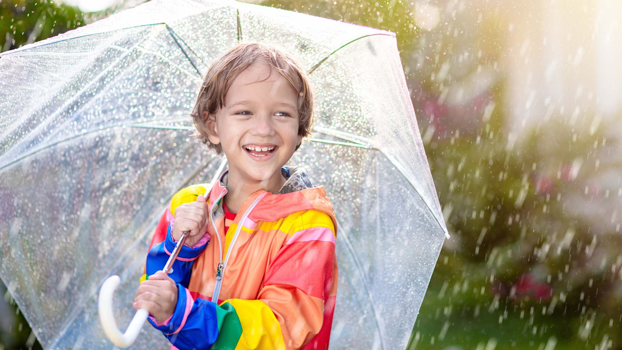 Lachendes Kind unter einem Regenschirm.
