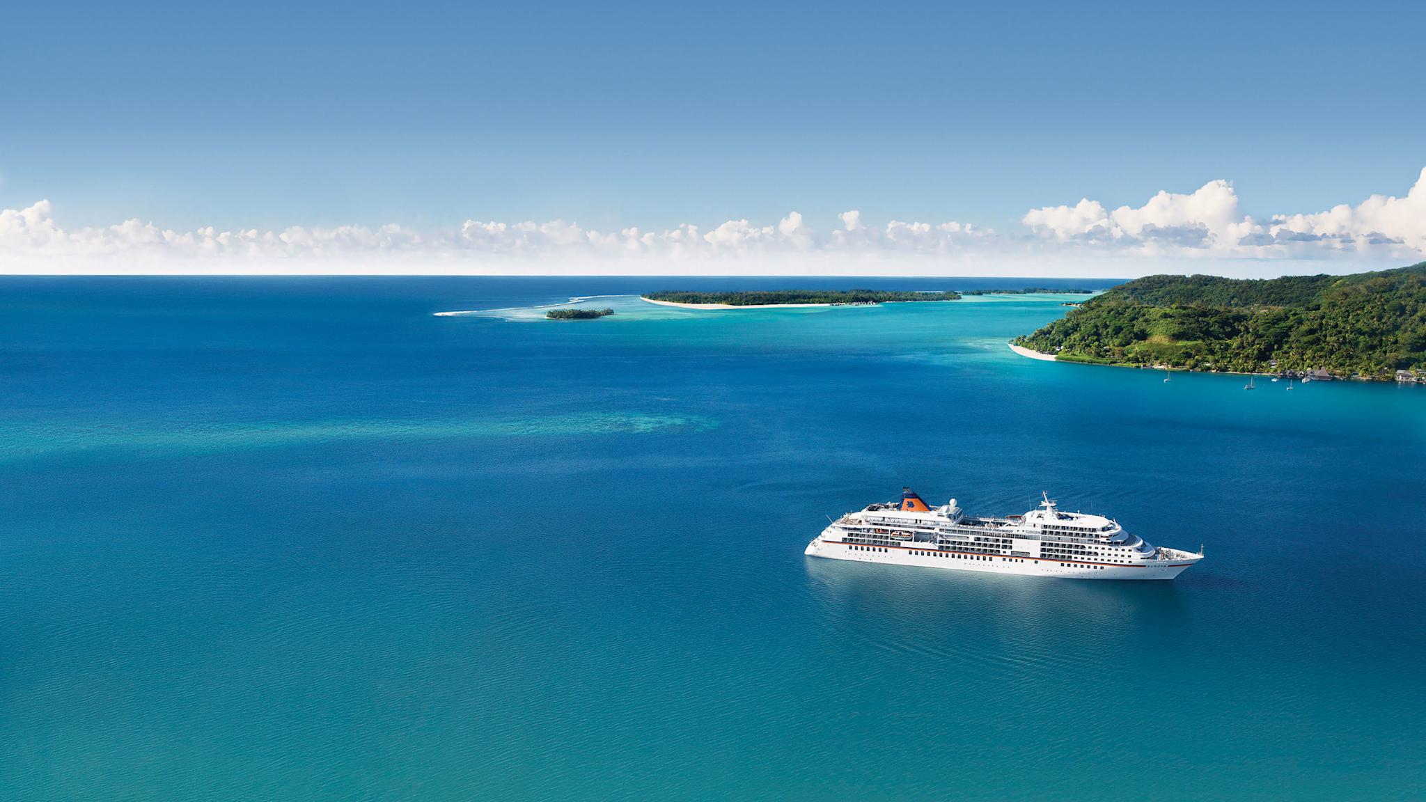 Kreuzfahrtschiff vor tropischen Inseln