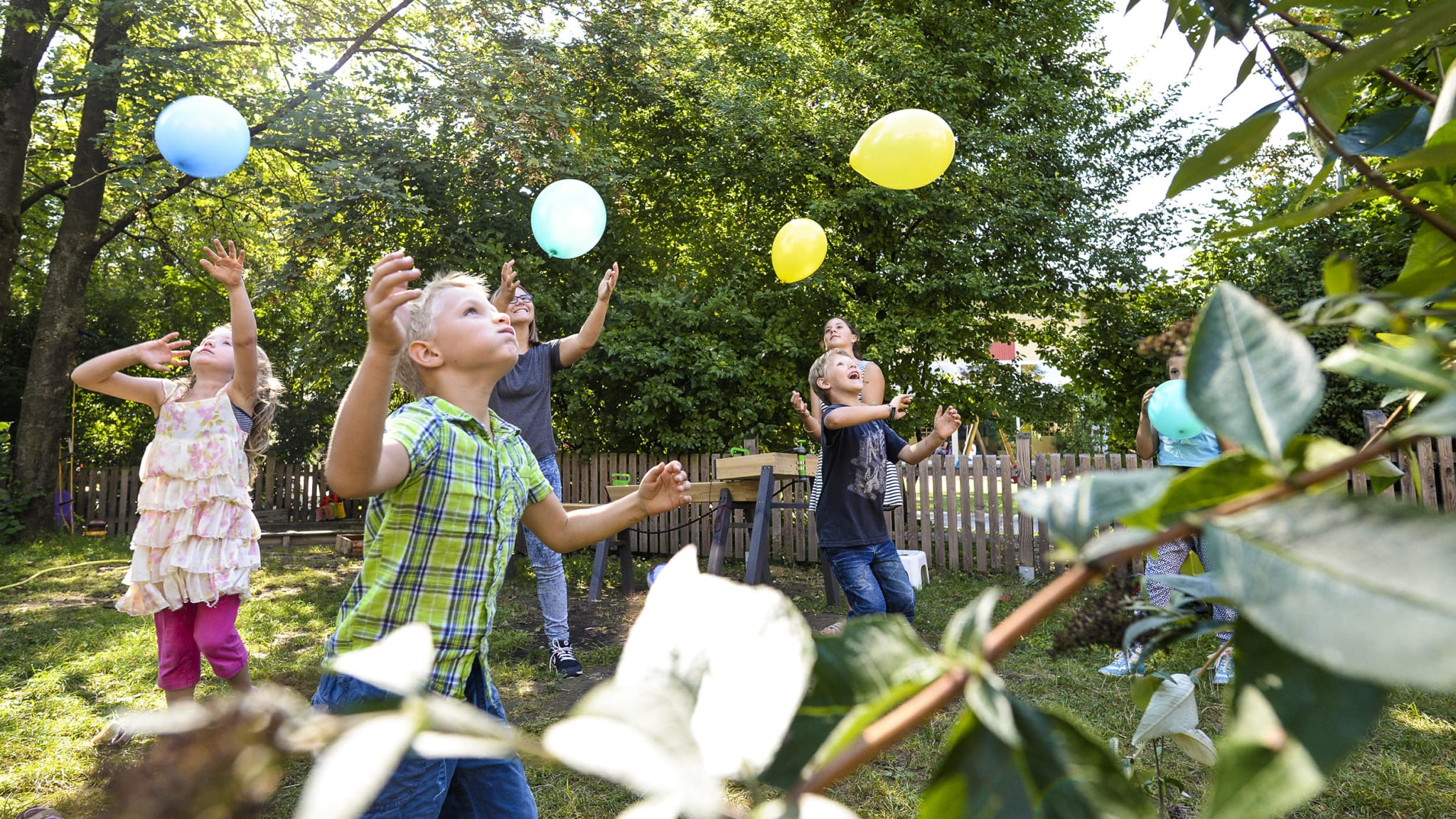 Kinder spielen mit Luftballons in einem Garten