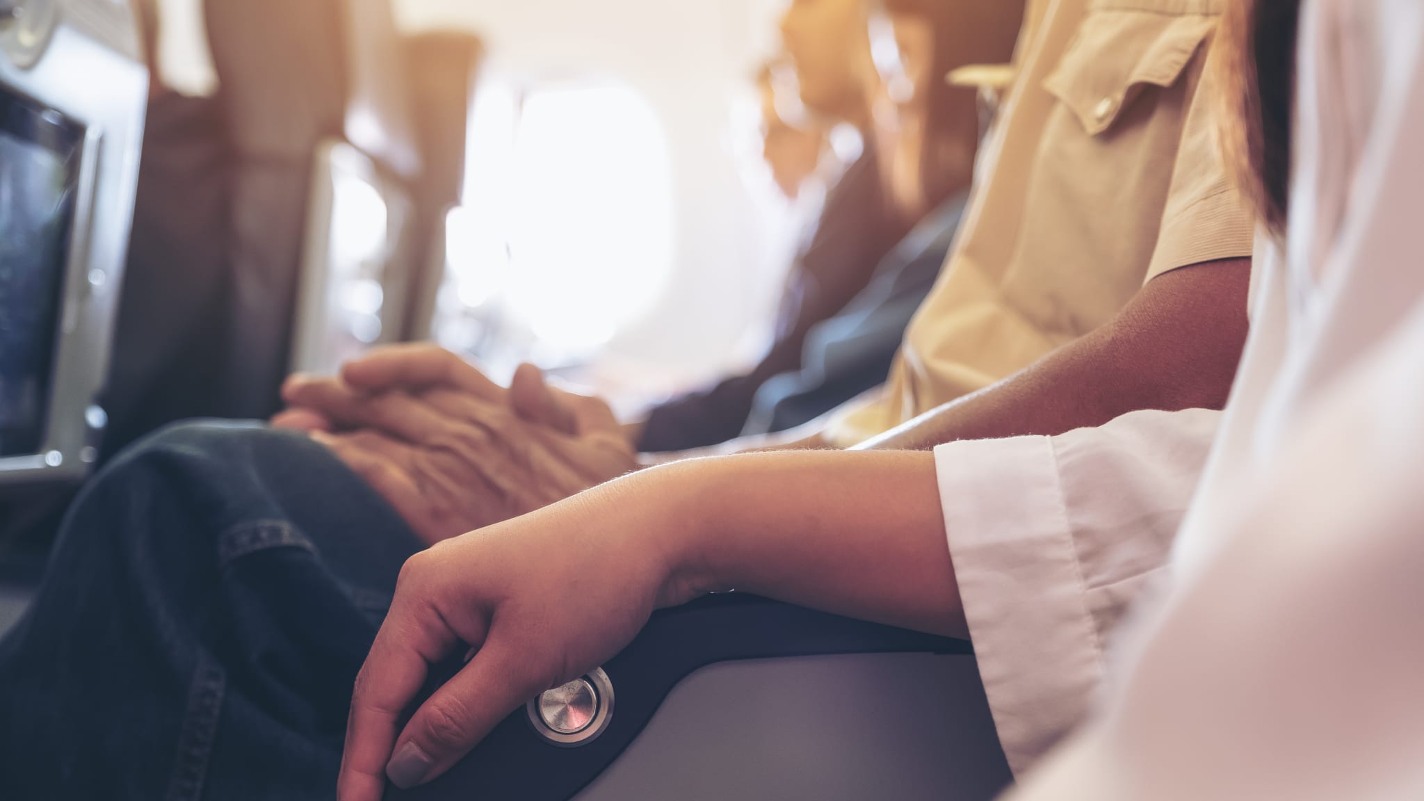 Frau und Mann teilen sich Armlehne im Flugzeug.