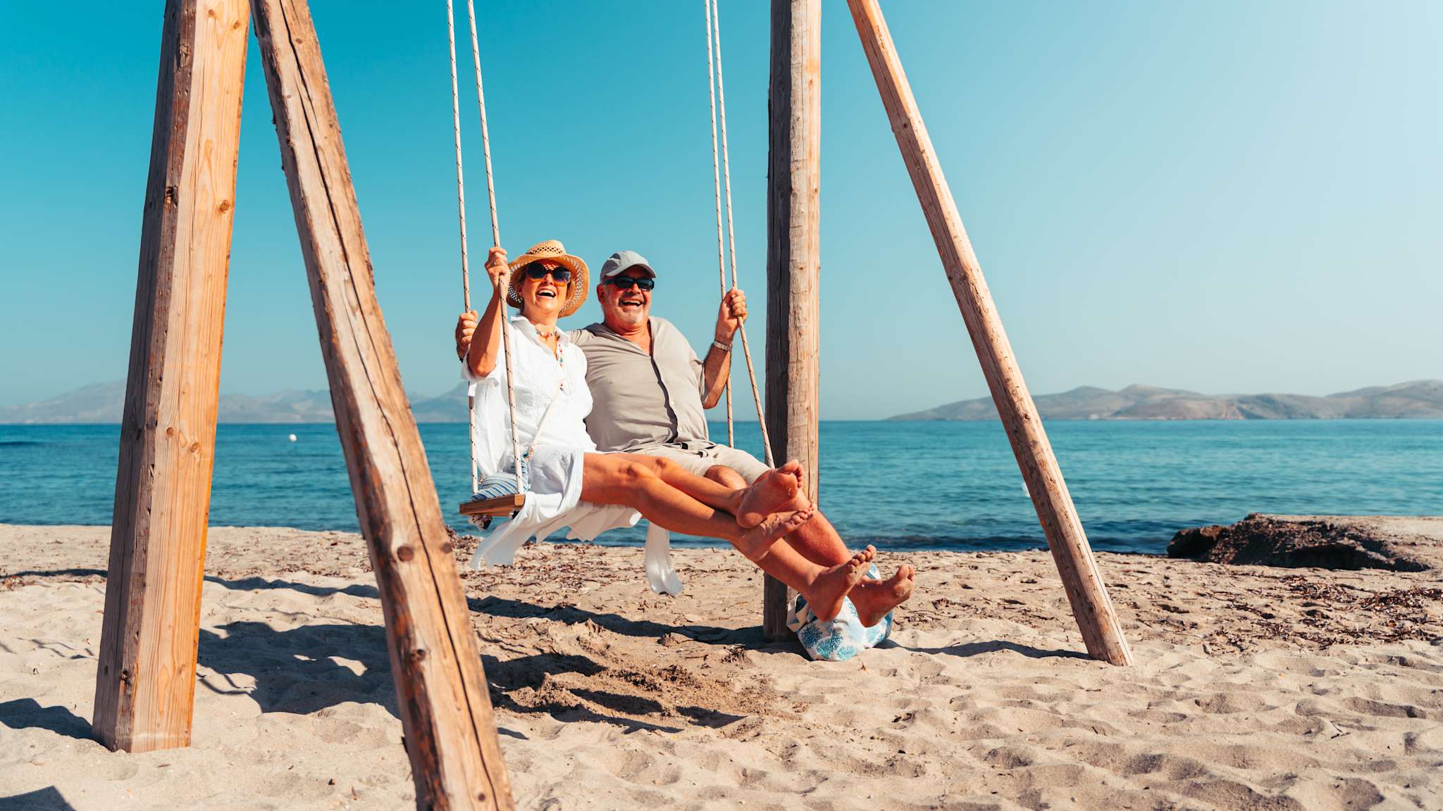 Älteres Paar am Strand auf einer Schaukel auf Kos, Griechenland.