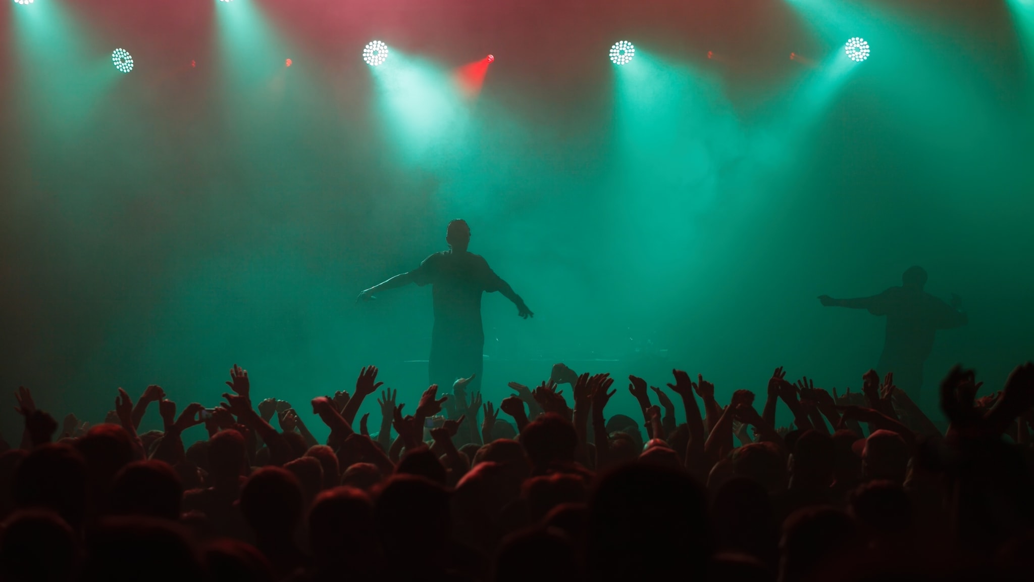 Rapper steht auf Konzertbühne vor einer feiernden Menschenmenge