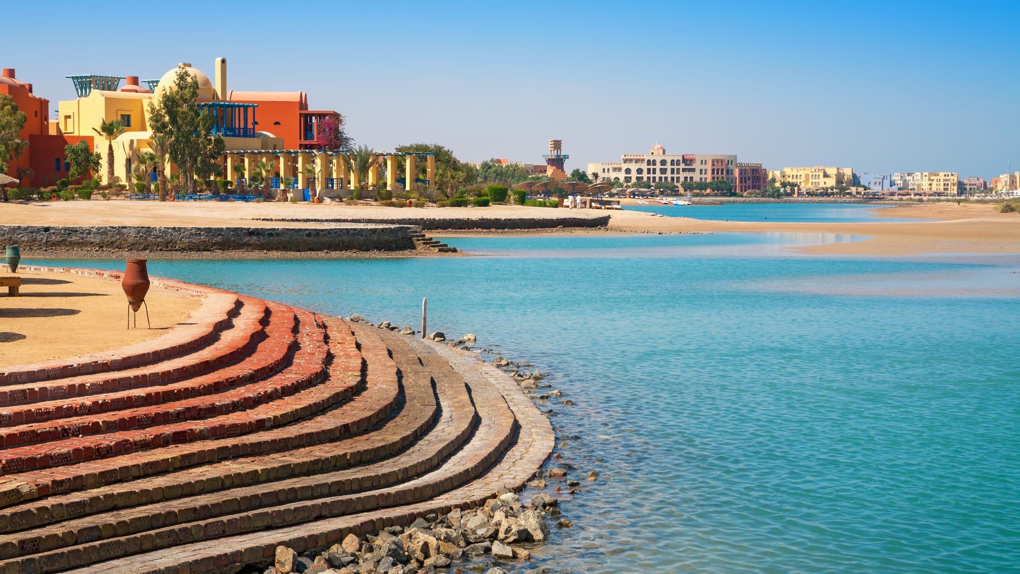 Eine Treppe führt hinuter an einen Strand mit türkisem Wasser