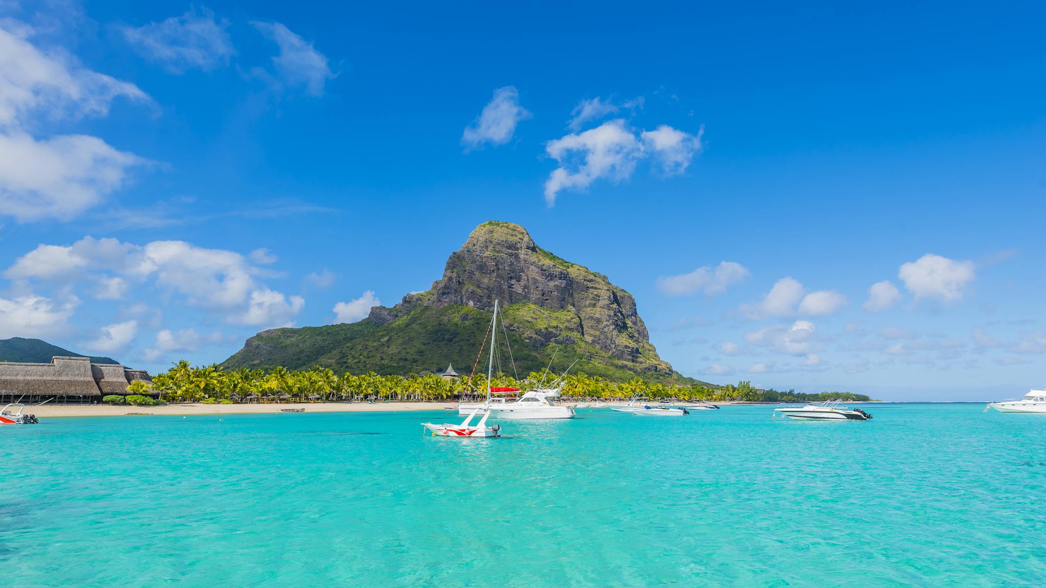 Ein Berg an einem Gewässer mit Booten im Vordergrund