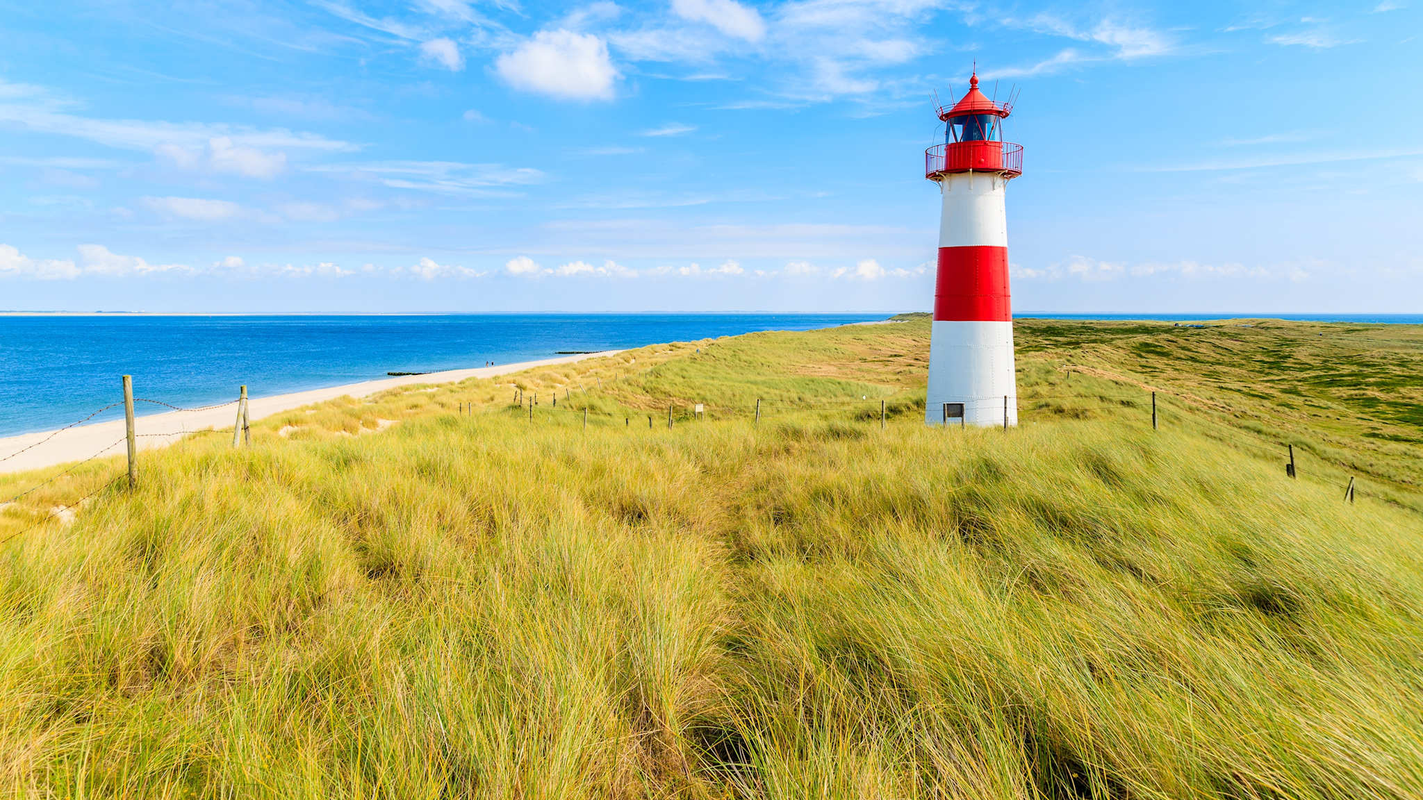 Ellenbogen lighthouse on sand dune against blue sky with white clouds on northern coast of Sylt island, Germany