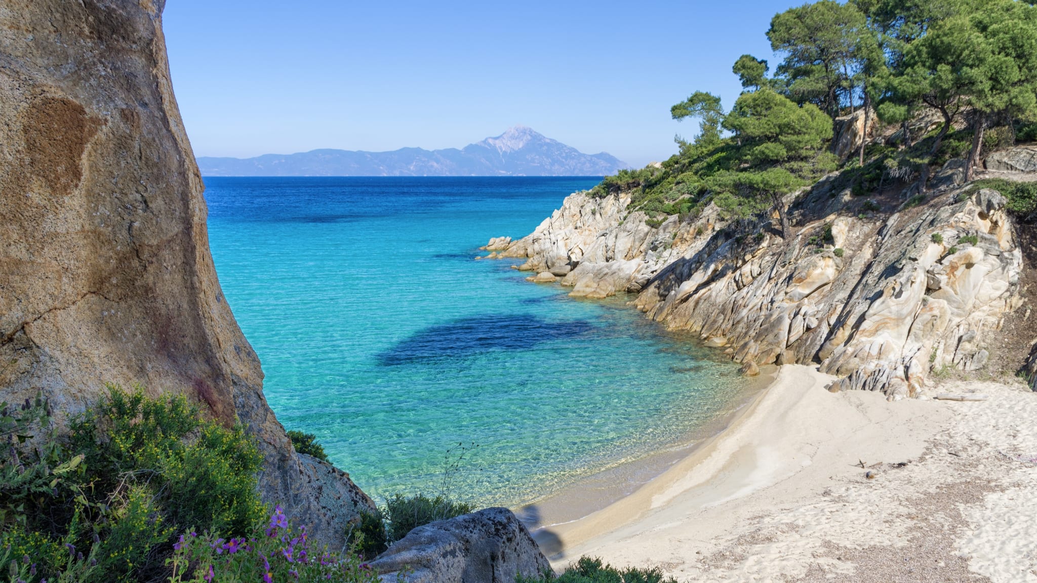 Eine azurblaue Meeresbucht mit klarem Wasser an einem Strand von Sithonia, Chalkidiki, Griechenland