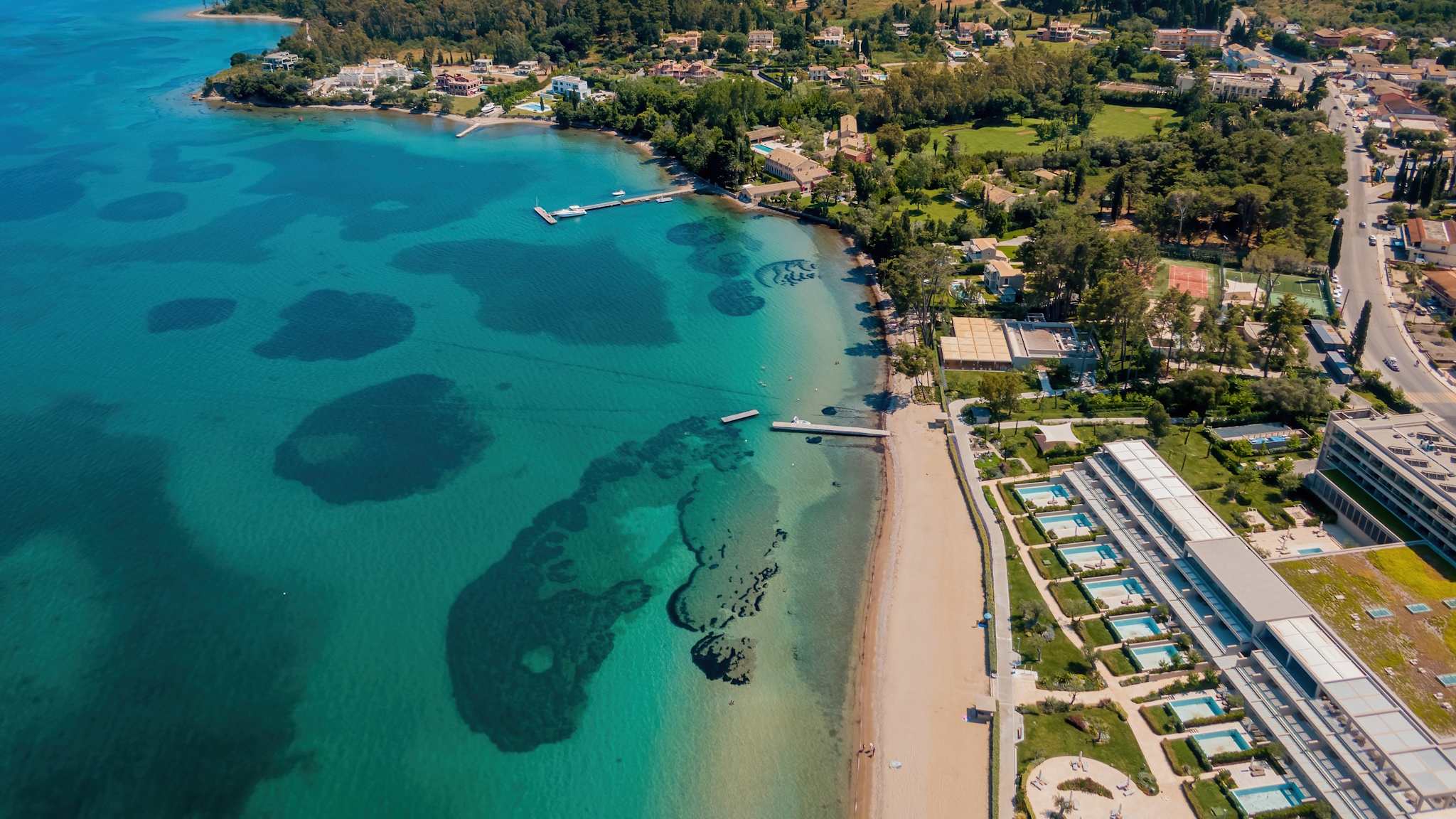 Ein Strand an einer Hotelanlage mit Stegen die ins Wasser führen