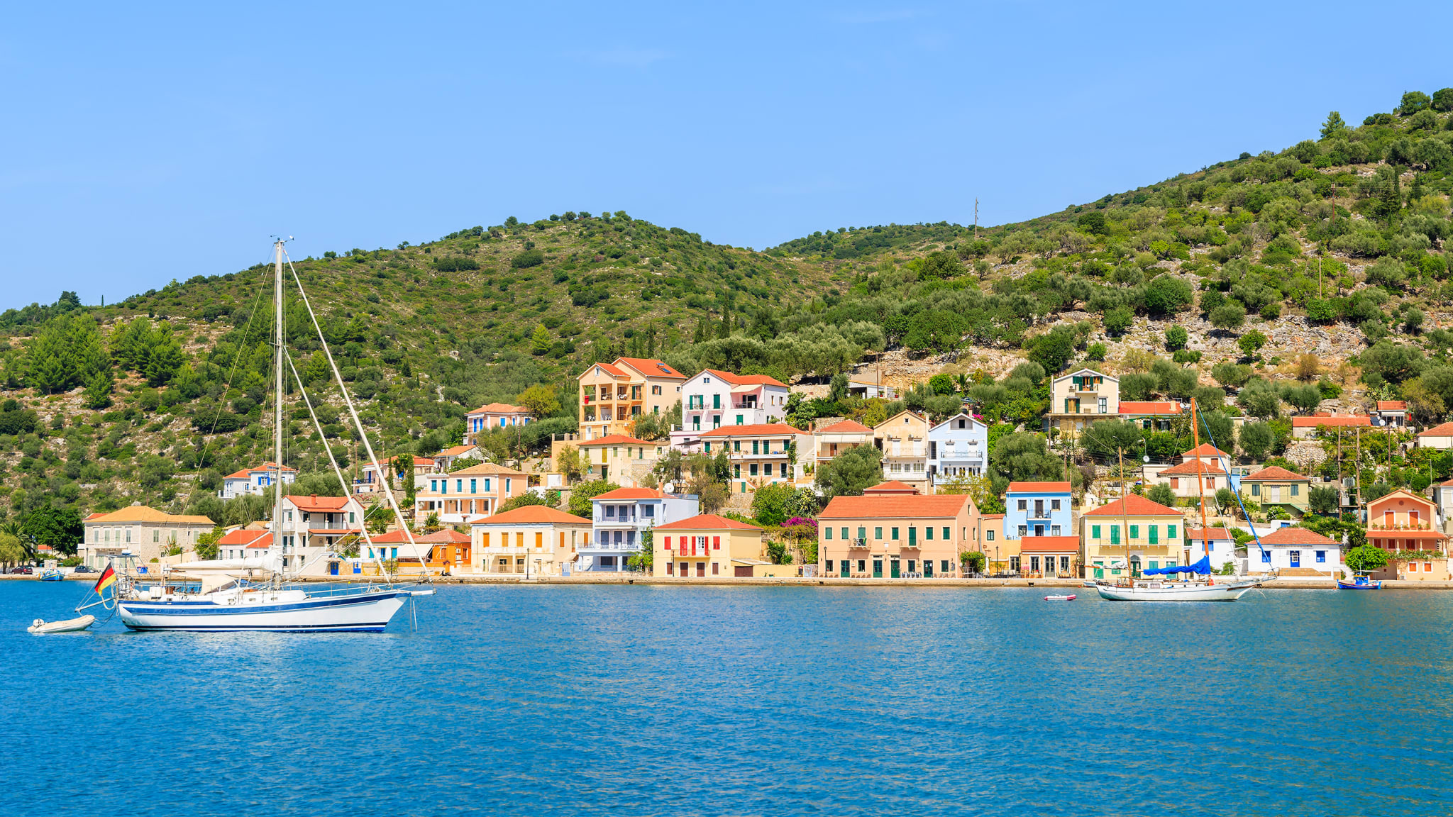 Yacht Boot am Meer mit bunten Häusern der Stadt Vathi im Hintergrund die Insel Ithaka, Griechenland