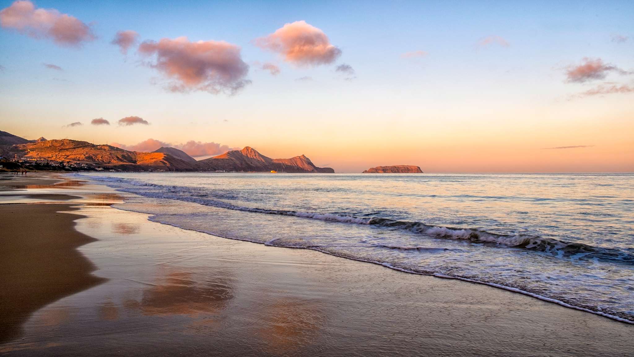 Ein leerer Strand bei Dämmerung mit Bergen im Hintergrund