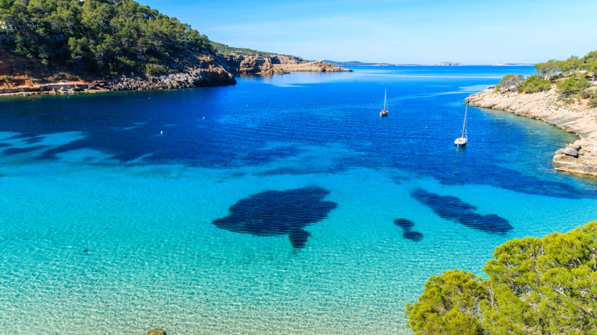 Klares Wasser und Boote in der BUcht von Cala Salada auf Ibiza