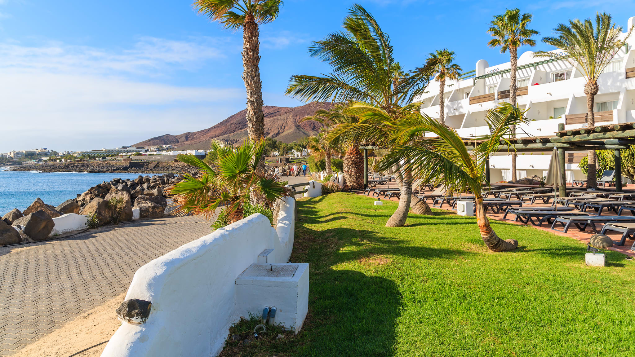Eine Strandpromenade mit Palmen und weißen Häusern