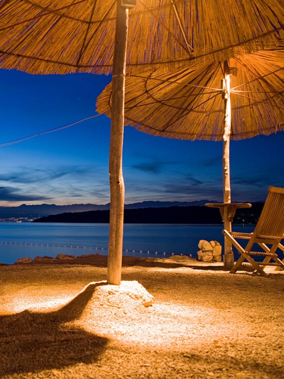 Beleuchtete Sonnenschirme in einer Strandbar, Njivice, Kvarner Bucht, Insel Krk, Kroatien, Europa