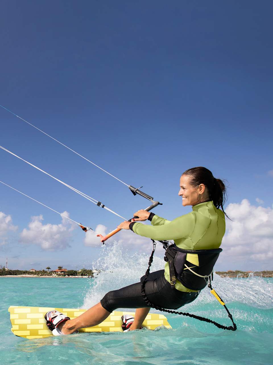 Frau hat Spass beim Kitesurfen in türkisfarbenem Meer © iStock.com/JMichl