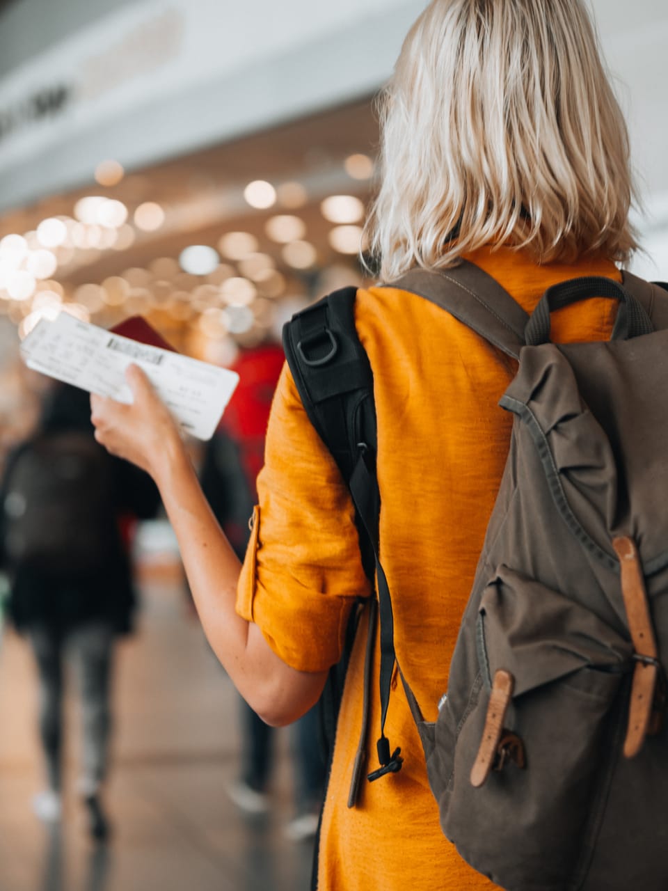 Frau mit Flugticket und Rucksack am Flughafen © iStock.com/Pyrosky