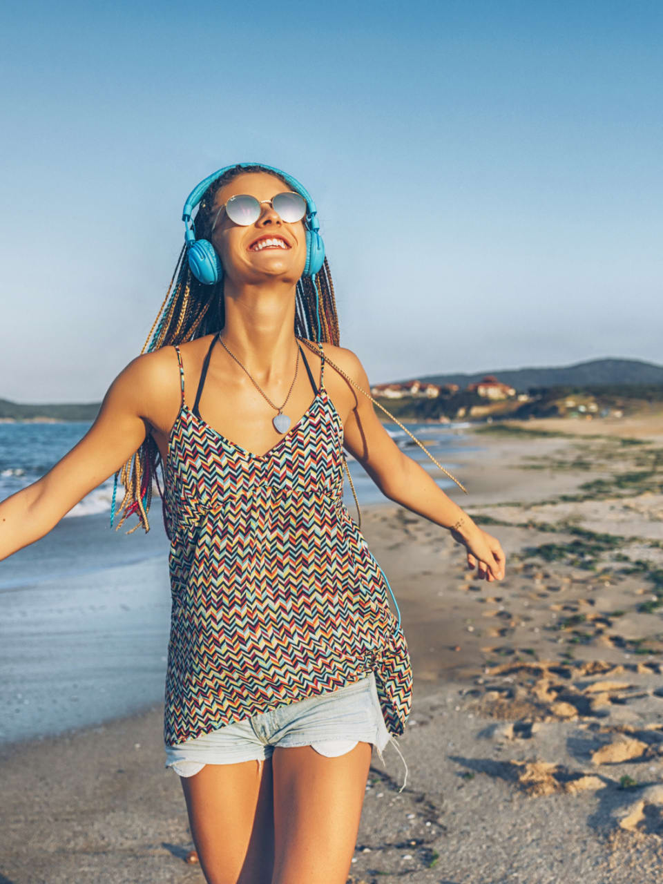Fröhliche junge Frau hört Musik mit Kopfhörern am Strand © iStock.com/Vladimir Vladimirov