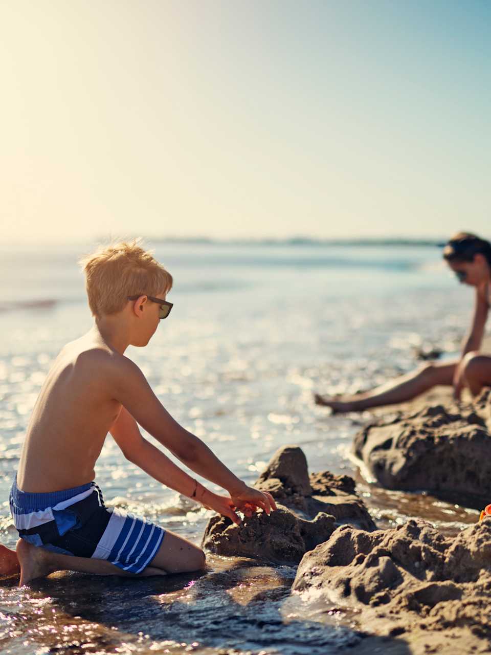 Kinder spielen am Strand und bauen eine Sandburg © iStock.com/Imgorthand