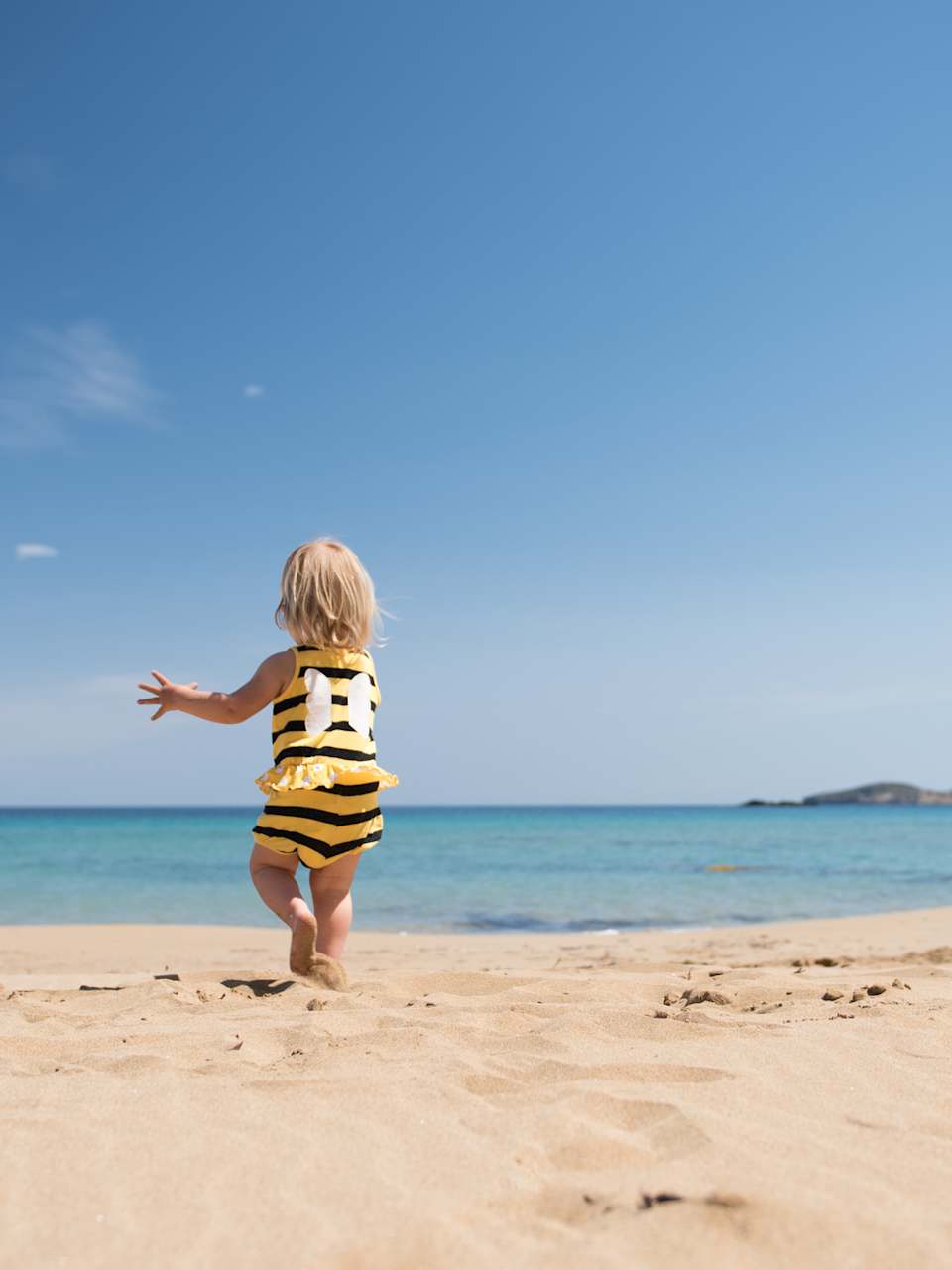 Kleines Mädchen rennt glücklich über einen Sandstrand im Urlaub © iStock.com/kamsta