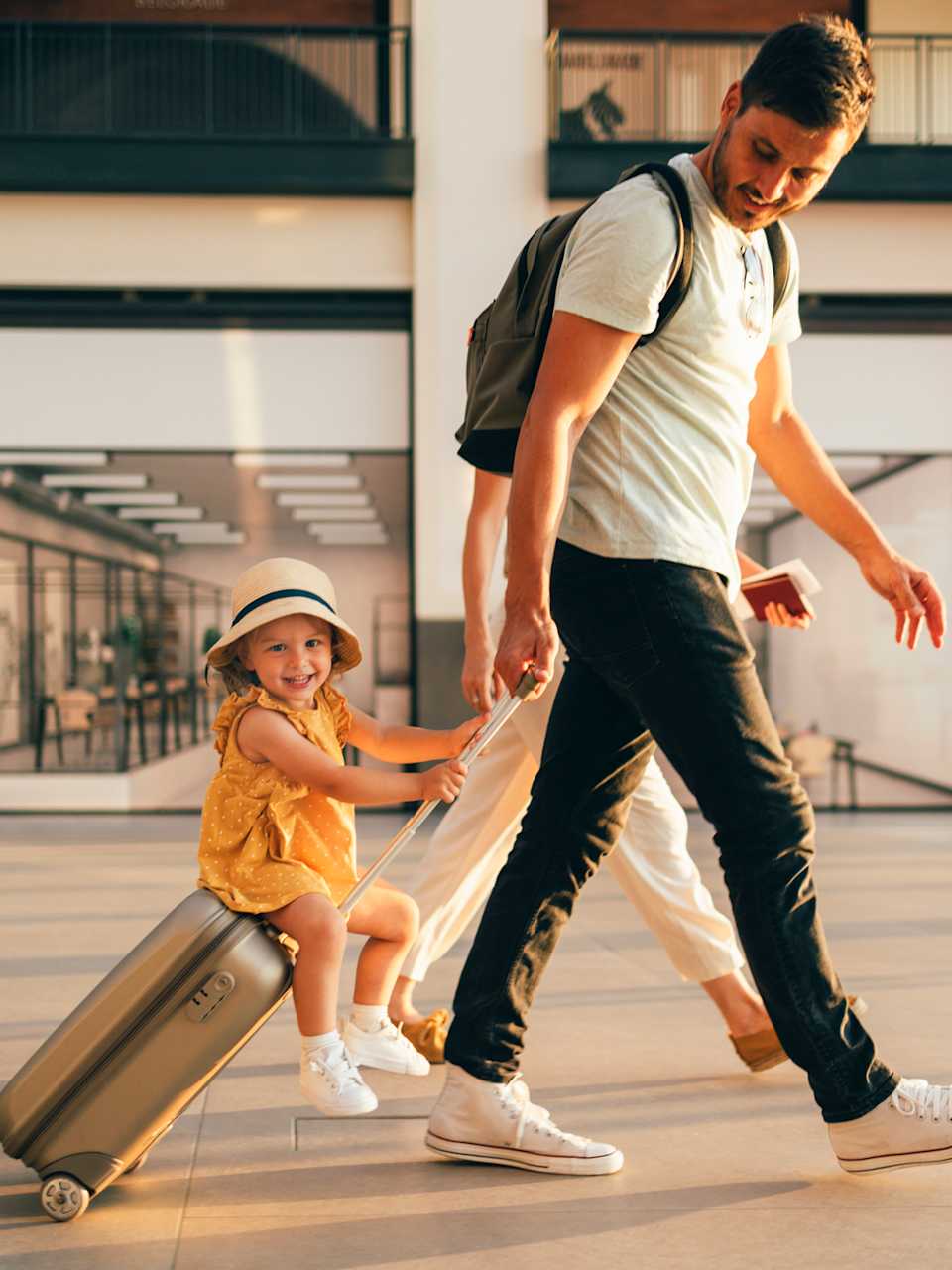 Vater zieht Kind, dass auf seinem Koffer sitzt durch den Flughafen © iStock.com/miniseries