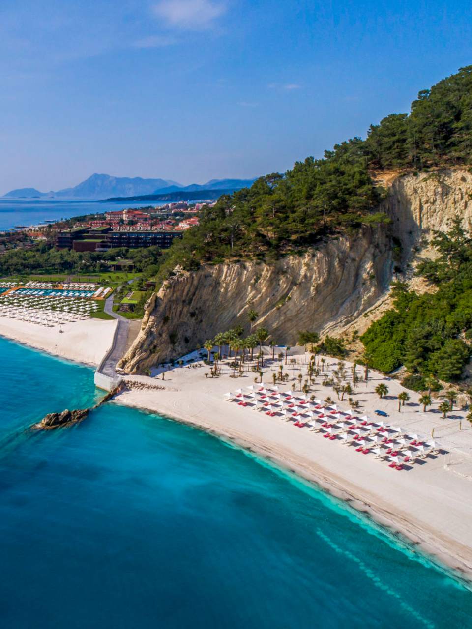 Strandabschnitt mit Felsen, Hotelgebäude und Meerblick im Maxx Royal Kemer Resort an der Türkischen Riviera