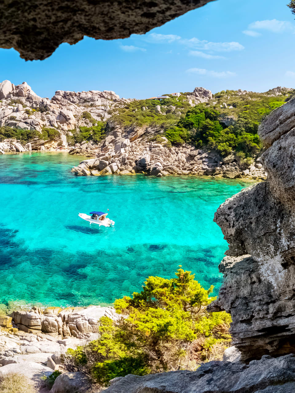 Boot auf klarem Wasser, umgeben von Felsen auf Sardinien in Italien