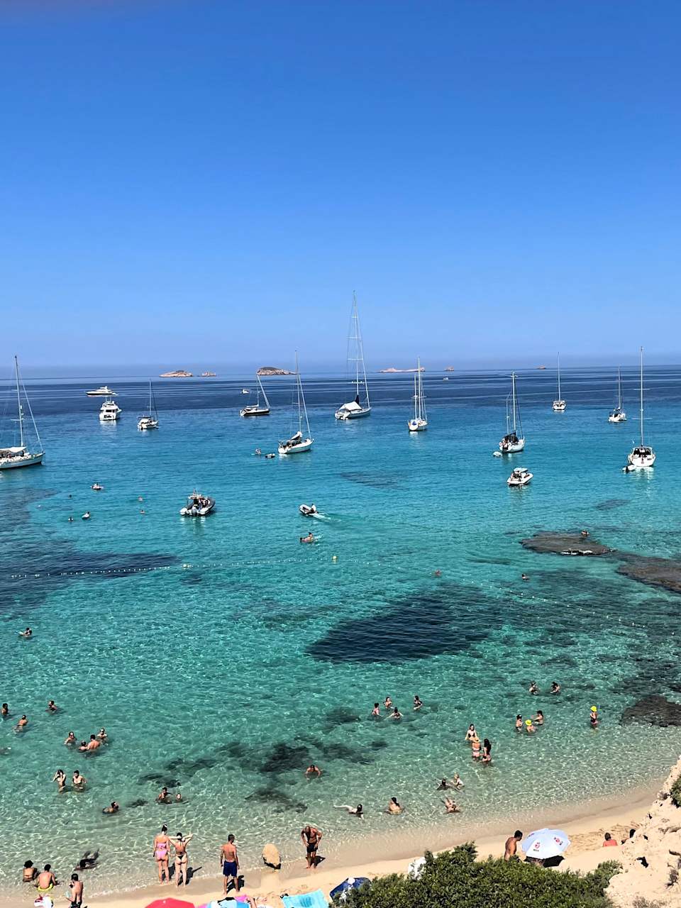 Boote und Touristinnen an der Cala Comte, Ibiza, Spanien