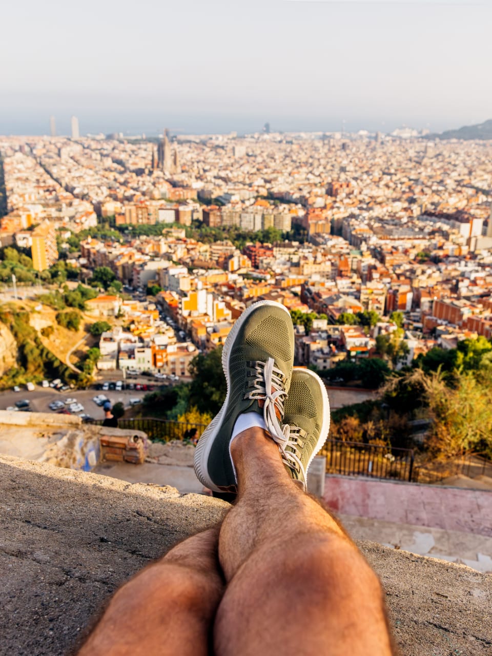 Ein Mann sitzt auf einer Mauer und schaut auf Barcelona.