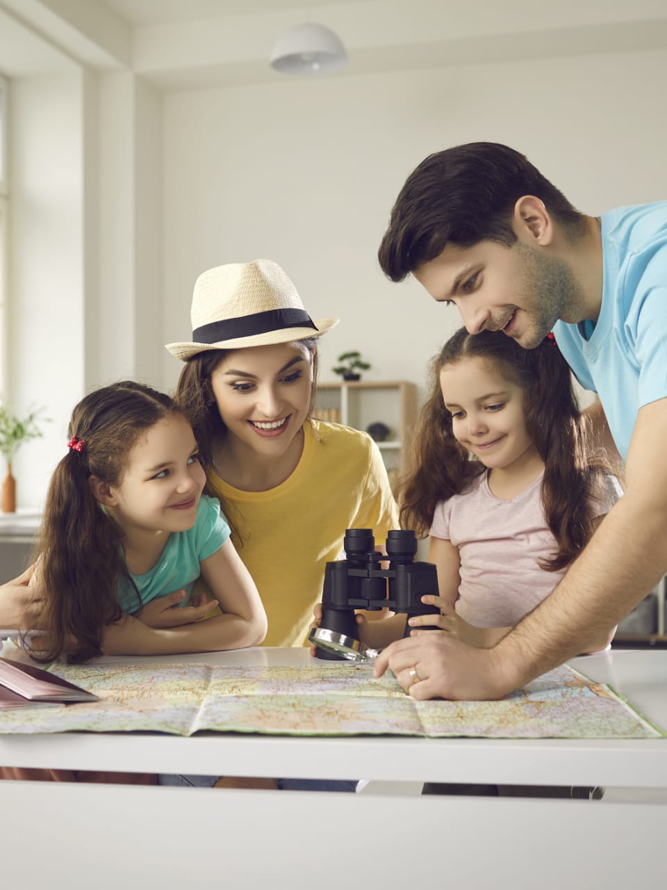 Eine Familie plant zuhause gemeinsam ihren Urlaub. © Lacheev/iStock / Getty Images Plus via Getty Images