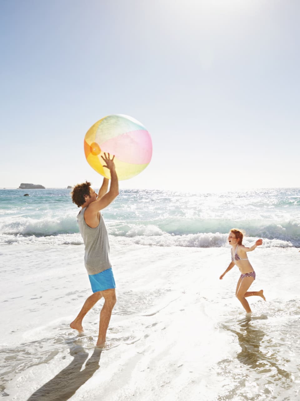 Eine Familie spielt mit einem Wasserball am Meer.