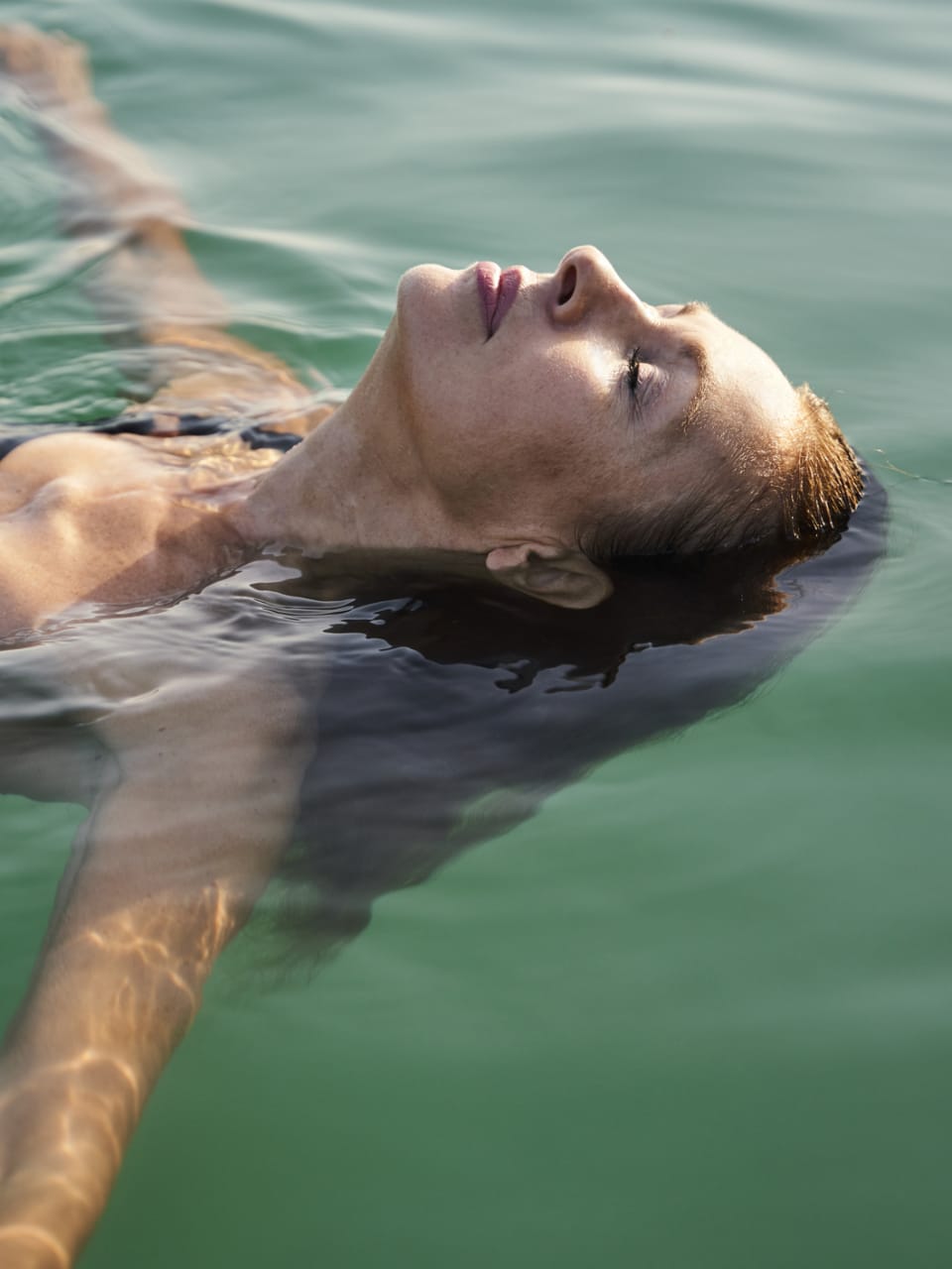 Eine Frau liegt auf dem Rücken im Wasser.