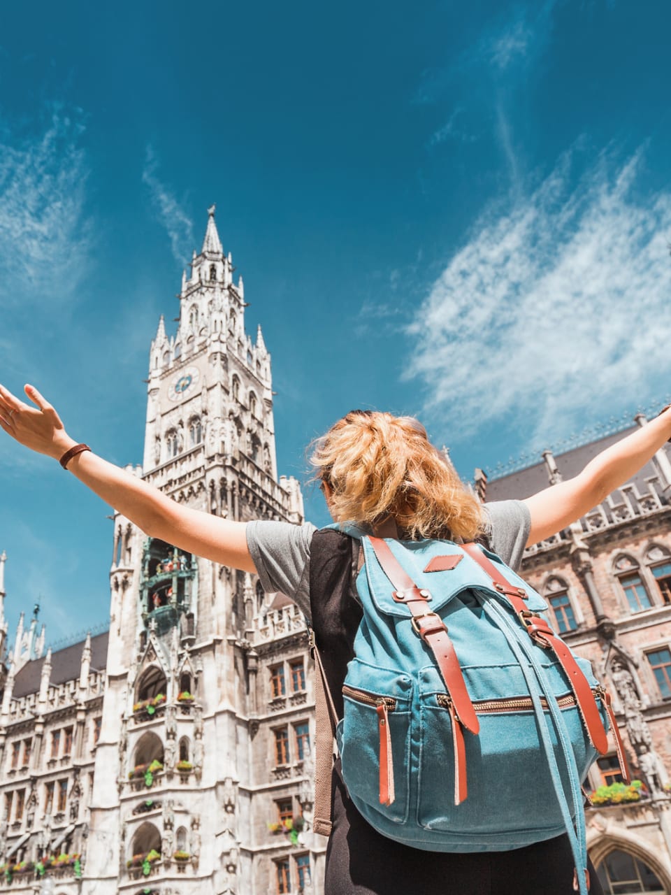 Eine Frau mit einem Rucksack steht vor dem Münchner Rathaus.