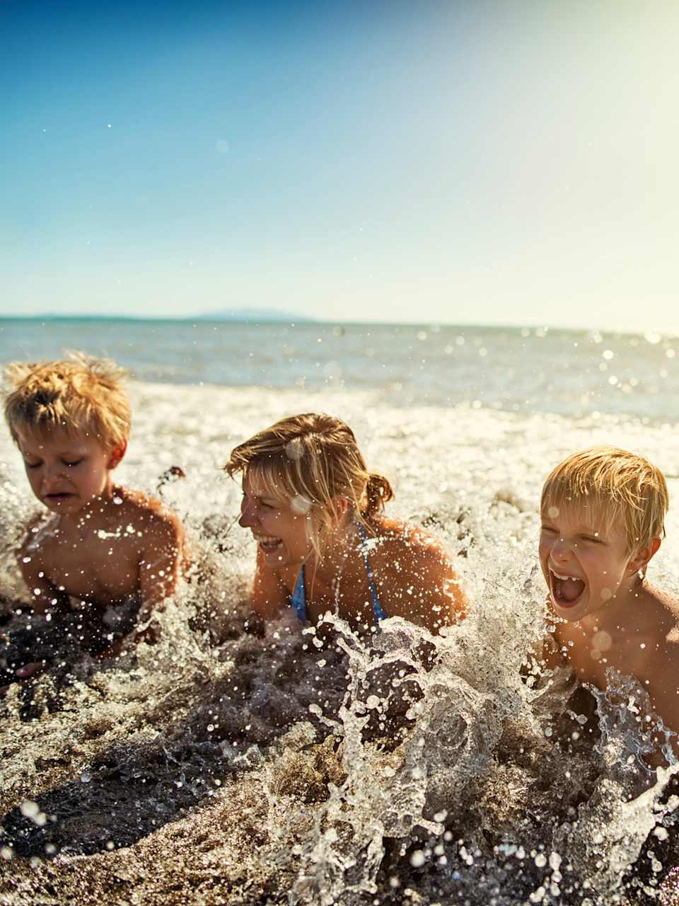 Familie liegt am Strand und planscht in Meereswellen in der Toskana, Italien